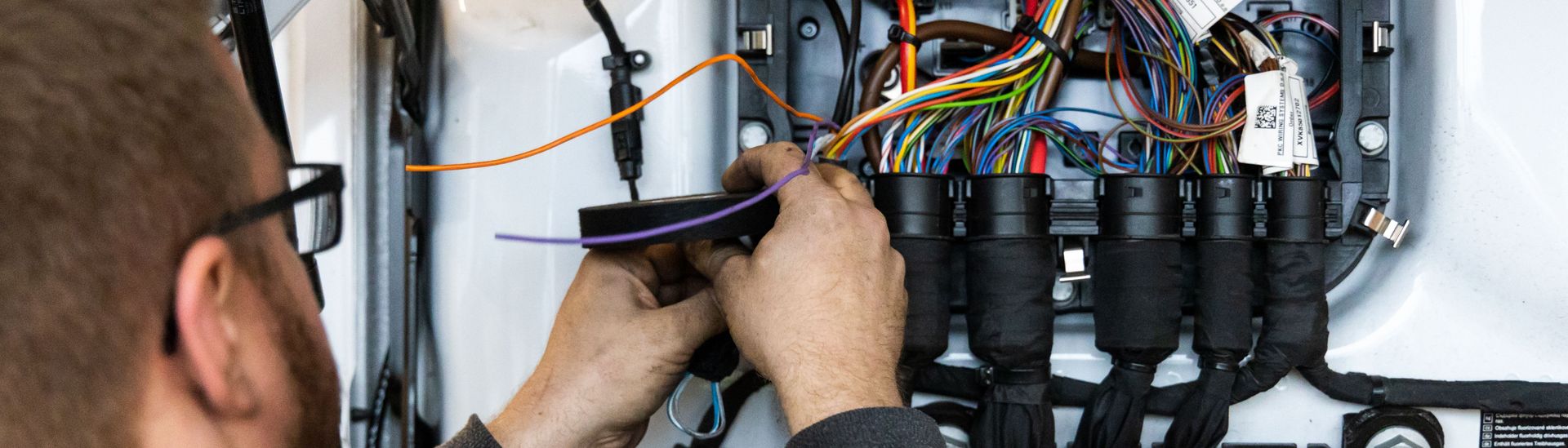 Fachmann verlegt Kabel in einem Sicherungskasten
